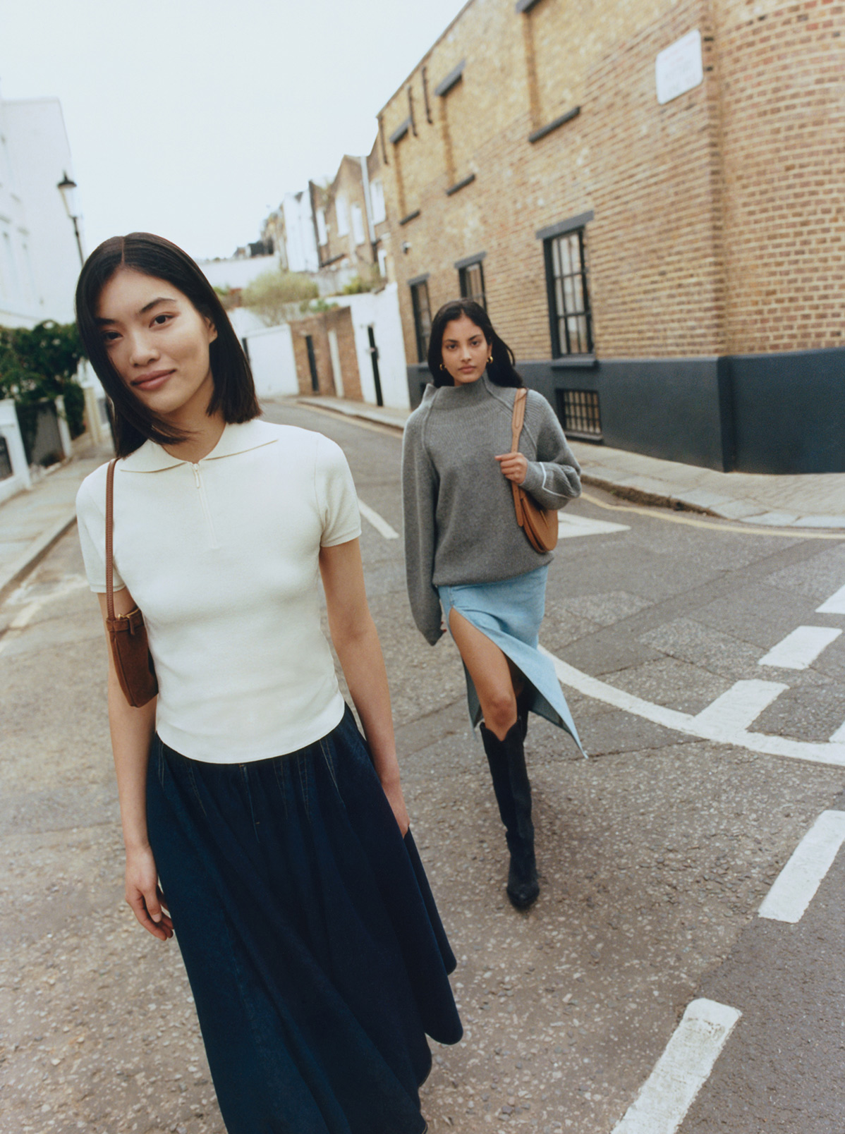 Two women walking down street wearing midi denim skirts
