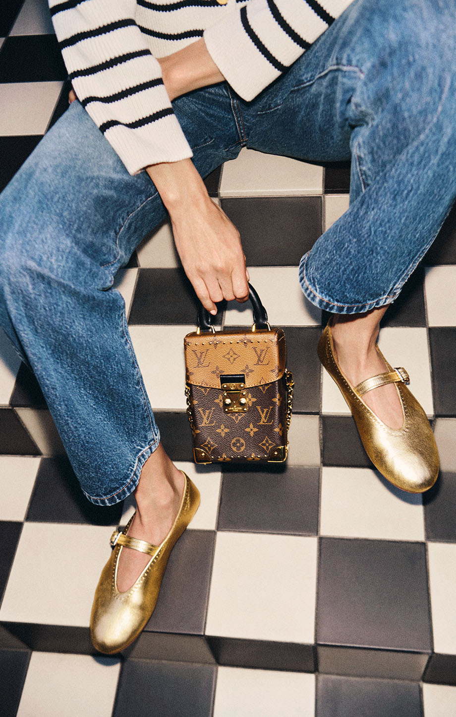 Woman sat on floor in gold ballet flats and small LV purse
