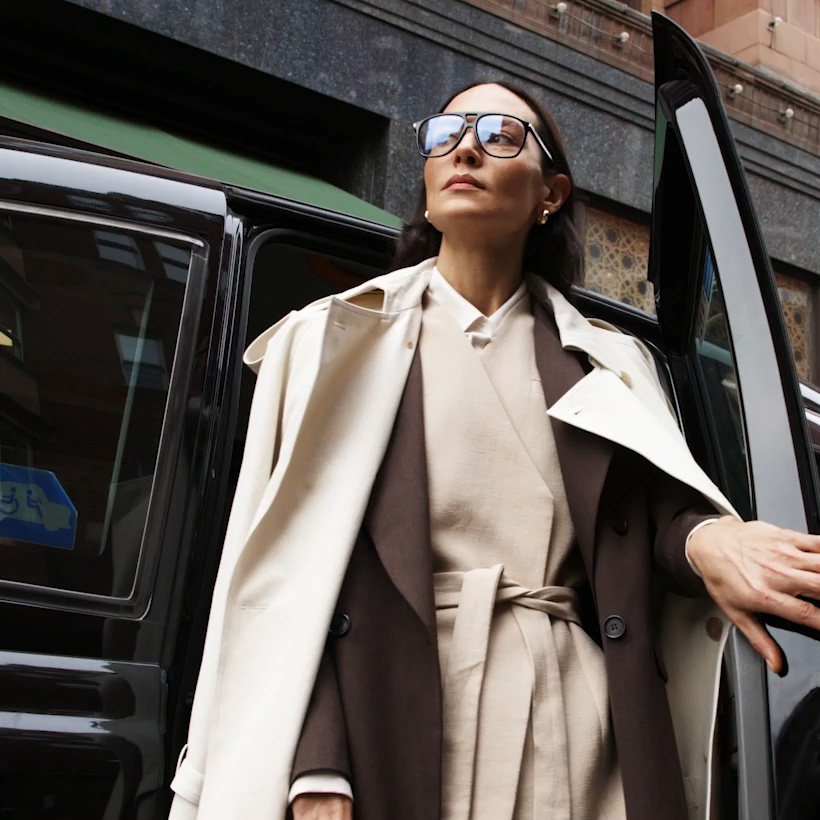 Woman exiting taxi in a tailored coat and suit