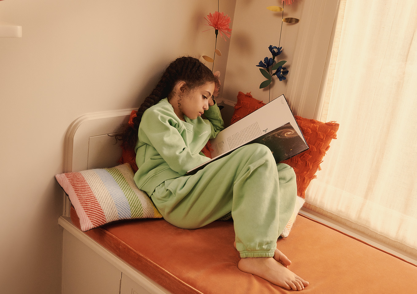 Girl curled up in green pyjamas and reading a book
