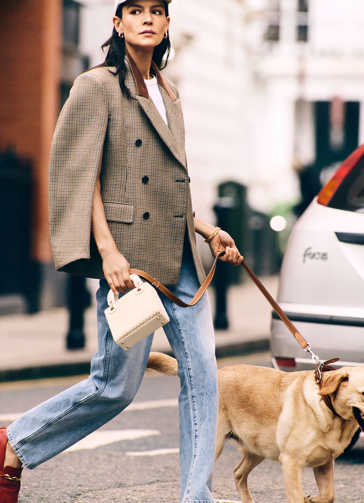 Woman out on the street walking her dog in a casual Maison Margiela blazer and jeans